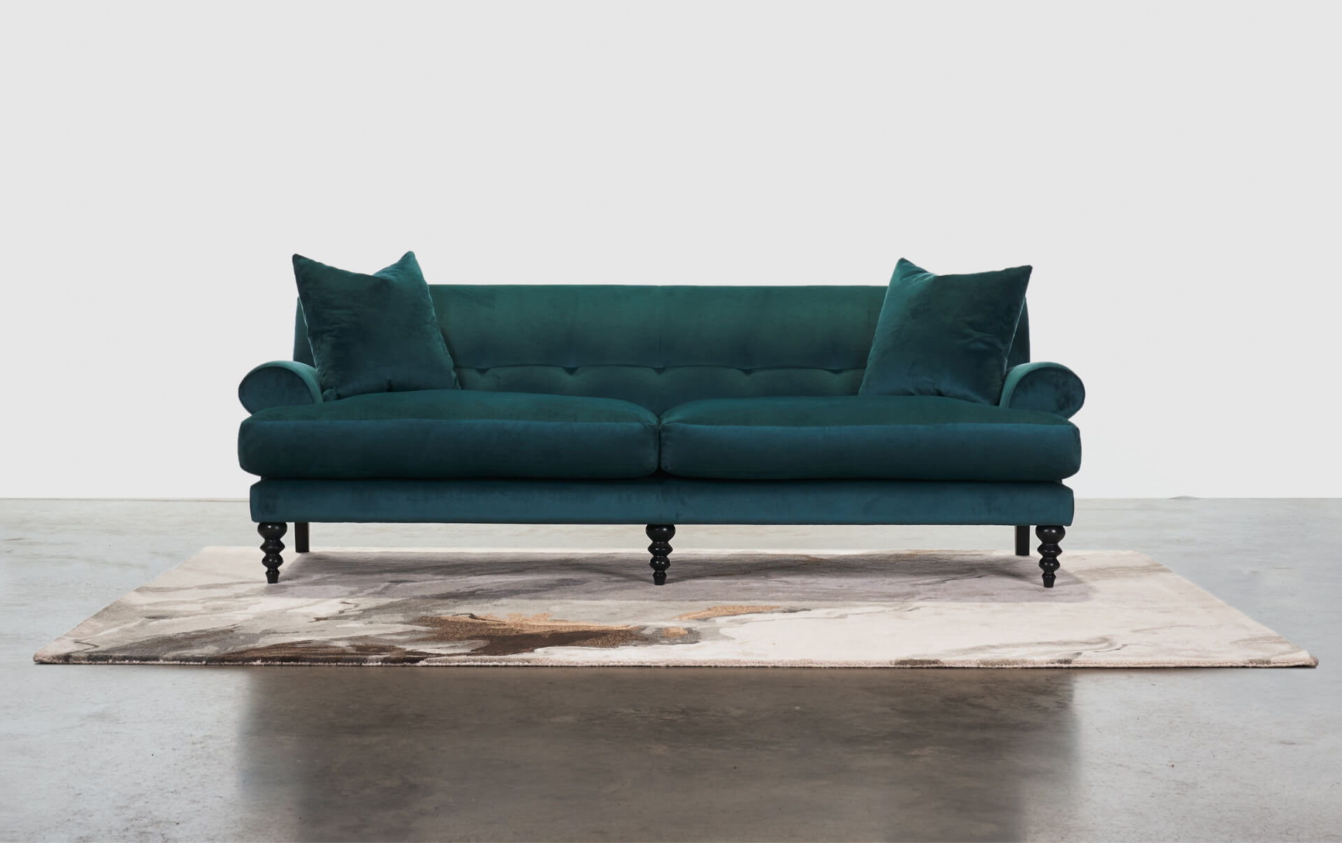 A dark green sofa placed on a light colored carpet.